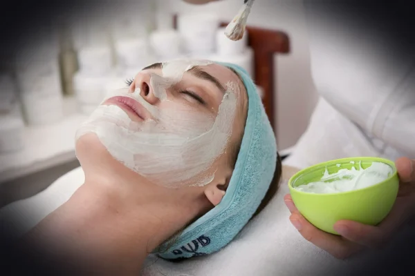 woman lying on blue towel with white cream on face