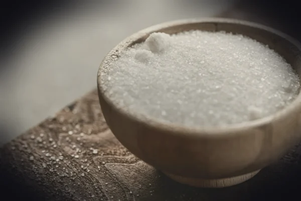 a wooden bowl filled with sugar on top of a wooden table