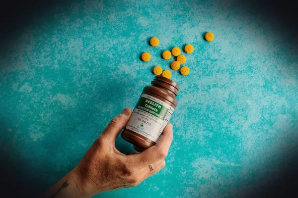a hand holding a bottle of vitamin pills