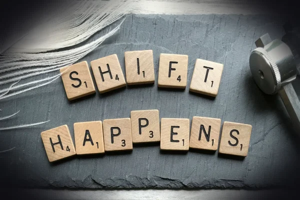 scrabble chips forming shift happens word near white feather