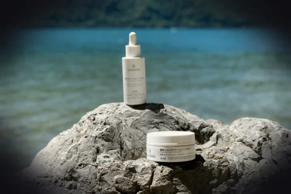Skincare products are displayed on a rock near the water.