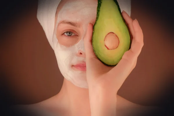 woman with white face mask holding green fruit