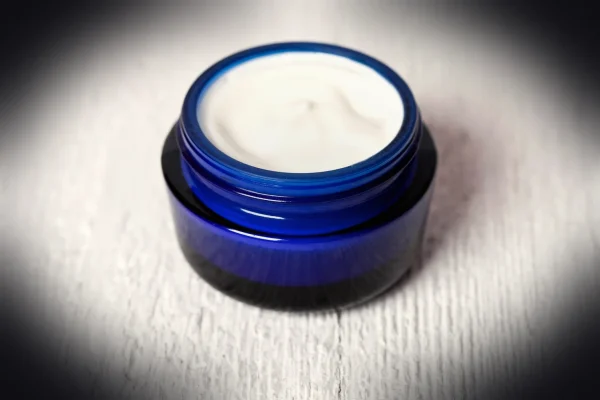 A jar of cream sitting on top of a white table