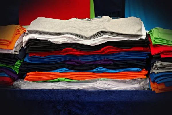 t-shirt, tee, clothing, garment, shirt, fashion, unisex, woman, man, top, casual, pile, pile of t-shirts, market, stall,