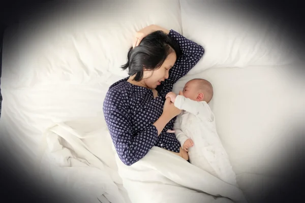 woman and baby lying on bed
