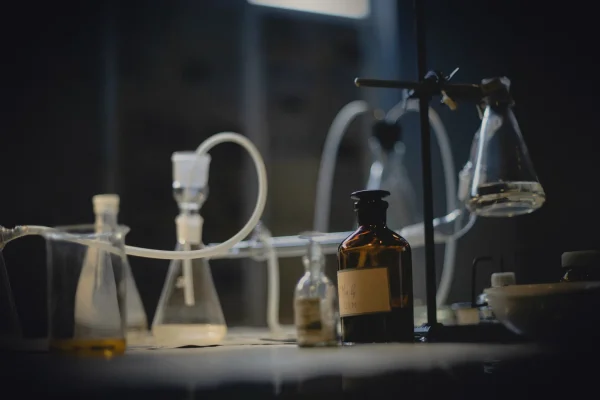 Laboratory glassware sits on a dark, illuminated table.