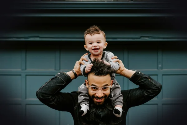 man in black leather jacket carrying boy in black leather jacket