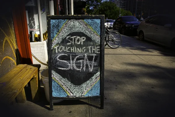 Chalkboard sign with 'stop touching the sign' written.
