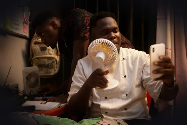 Man holds fan while taking selfie with phone