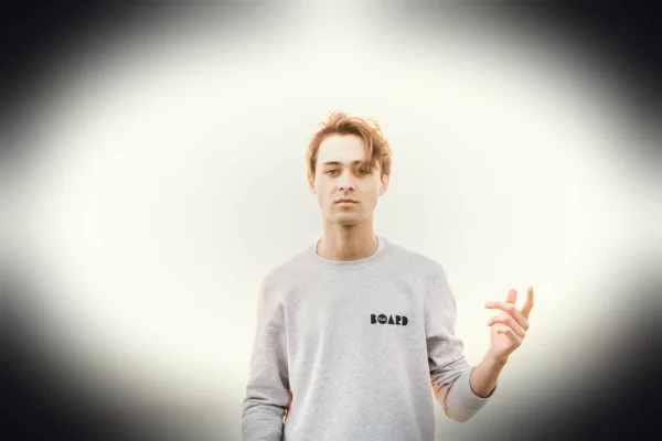 man in gray sweatshirt raising his left hand