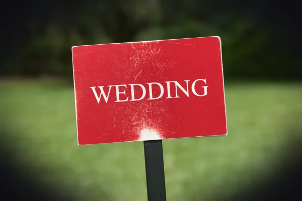 a red wedding sign sitting on top of a black pole