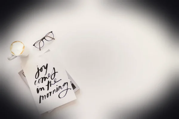 joy comes in the morning card beside coffee and eyeglasses