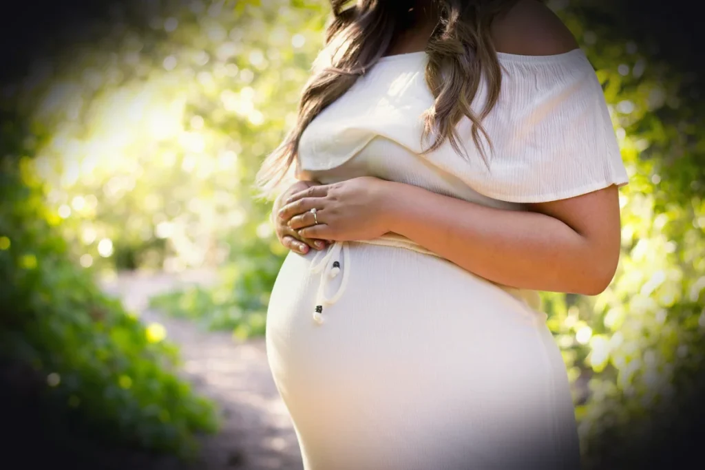 pregnant woman standing near green plants