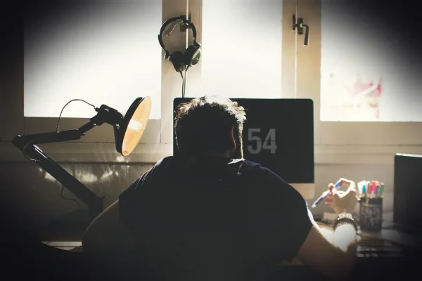 man, chair, computer, desk, sit, seated, electronics, indoors, lamp, laptop, room, workspace, home office, work from hom